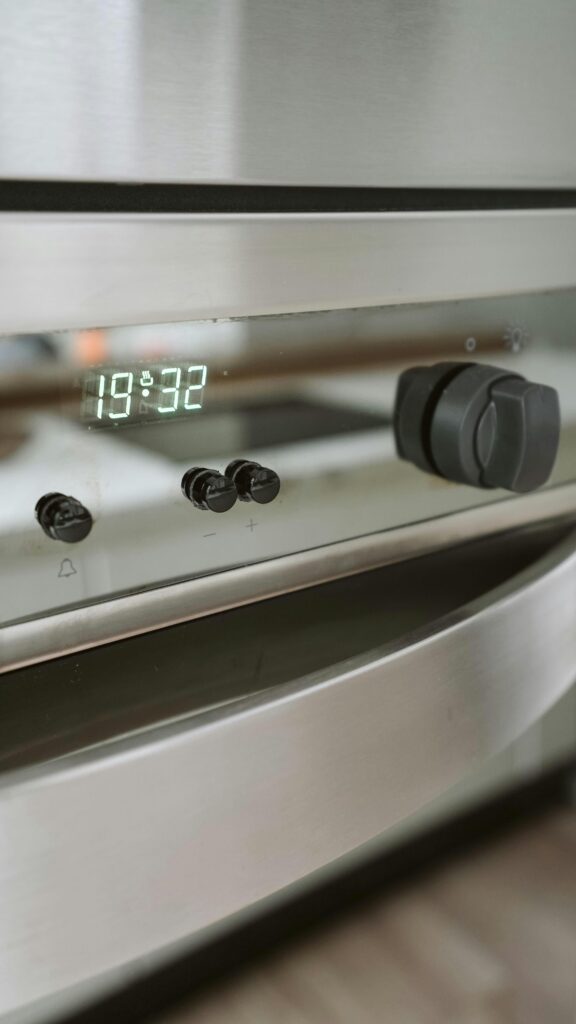 Close-up view of a modern stainless steel kitchen oven with digital display and control knobs.